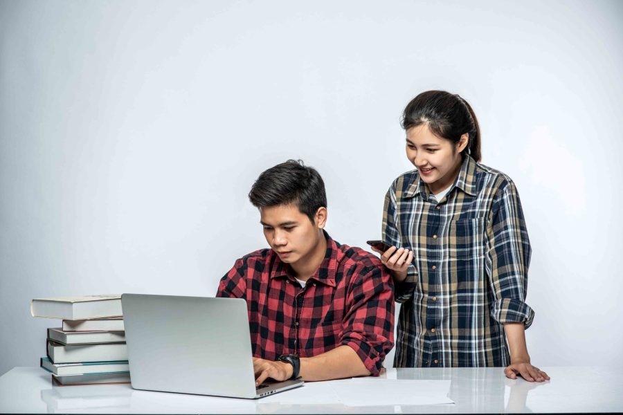 Women teach men how to work with laptops at work.